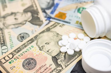 Tedavi için beyaz yuvarlak tedavi hapları, paralı ağrı kesici veya uyuşturucu, Amerikan doları banknotları, pahalı ilaç ve sağlık sigortası konsepti, yakın plan görüş.