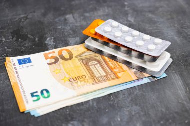 Tablet veya hap içeren su toplayıcı paketler, antibiyotik, ağrı kesici veya uyuşturucu veya para, Avrupa para birimi banknotları, pahalı ilaç ve sağlık konsepti, yakın çekim görünümü.