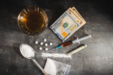 Bardakta alkol içkisi, bir doz uyuşturucu, beyaz hap, narkotik tozu ve siyah arka planda Amerikan doları nakit para içeren şırınga. Bağımlılık, istismar ve kötü alışkanlık kavramı..