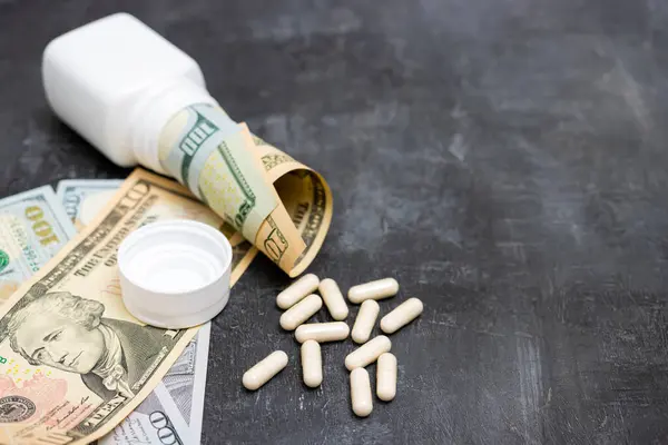 stock image Capsules, pills, painkiller or drugs with money, US dollar banknotes, expensive medicine and healthcare concept, close-up view.