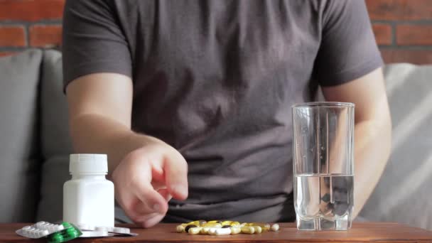 Hombre Sentado Casa Sofá Tomando Pastillas Cápsulas Vitamínicas Bebiendo Agua — Vídeo de stock