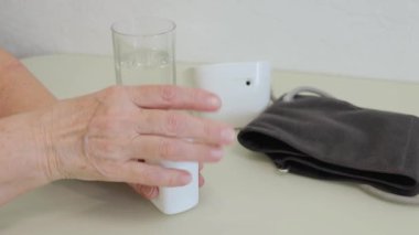 Yaşlı yetişkin bir kadın ilaç alıyor, elinde şişe tutuyor ve beyaz ağrı kesici haplar veriyor, tedavi için kapsüller, antibiyotikler veya vitaminler eski kırışık el, sağlık ve ilaç konseptine konuyor.