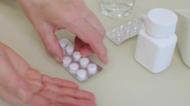 Yaşlı yetişkin bir kadın ilaç alıyor, elinde ağrı kesici haplar, tedavi için kapsüller, antibiyotikler veya kırışık el, sağlık ve ilaç konseptinde vitaminler tutuyor.