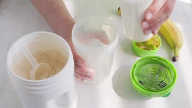Erkek eli sütü karıştırıcıya döküyor, protein içeceği yapma süreci, kavanoza beyaz süt veya soya proteini tozu, spor beslenmesi.