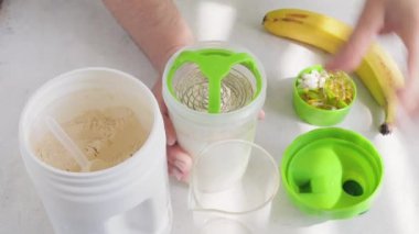 Erkek elleri süt ve süt veya soya proteini tozu ile bir karıştırma, muzlu içecek yapma süreci, sağlıklı spor beslenme