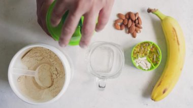 Erkek el protein sütlü muzlu smoothie bardaktan bardağa, beyaz buğday veya soya proteini tozuna, bir kavanoza, spor beslenme, üst görünüm