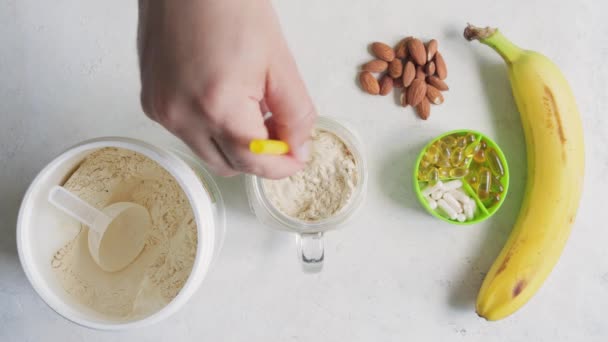 将白色乳清或豆蛋白粉混合在玻璃瓶中的男性手 与牛奶香蕉冰沙 运动营养 顶视图混合 — 图库视频影像