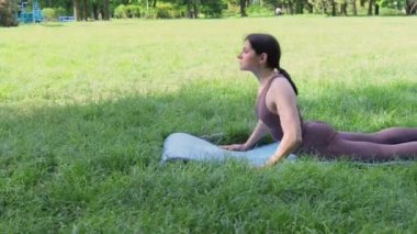 Genç çekici, sportif bir kadın dışarıda yoga yapıyor. Sabah köpek pozu veriyor. Sağlıklı yaşam tarzı kavramı.