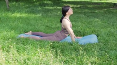Genç çekici sporcu kadın dışarıda yoga yapıyor, yukarı doğru bakıyor ve köpek pozu veriyor yaz parkında, sağlıklı yaşam tarzı konsepti.