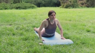 Genç çekici, sportif bir kadın dışarıda yoga yapıyor. Sabah köpek pozu veriyor. Sağlıklı yaşam tarzı kavramı.