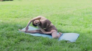 Genç, çekici, sportif bir kadın. Egzersiz yapıyor, yoga yapıyor, yaz parkında egzersiz yapıyor, sağlıklı yaşam tarzı kavramları geliştiriyor.