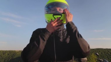 Motosikletli kadın motosiklet sürücüsü açık havada yeşil başlık takıyor, yakın çekim manzaralı.