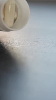 Tedavi için beyaz tıbbi kapsüller ya da konteynırdan siyah arka planda bir elde düşen ilaçlar, yakın çekim, yavaş çekim