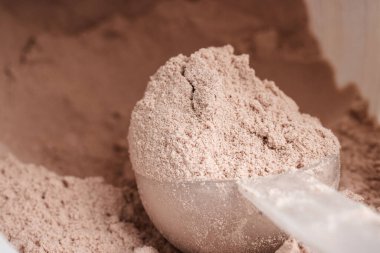 Bir kepçe çikolatalı süt proteini plastik bir kavanozda izole edilir..