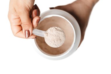 Bir kadının elinde ölçüm kaşığı ile kavanozun üzerinde süt proteini tozu var. Protein içeceği kokteyli yapıyor. Beyaz arka planda izole edilmiş..