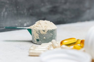 Beyaz protein tozu ölçme kaşığında, beyaz amino asit kapsülleri, vitaminler ve sarı kapsüller omega 3, sağlıklı beslenme ve vücut geliştirme gıda takviyeleri..