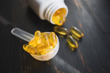 Omega 3 balık yağı sarı kapsüller plastik bir kaşık içinde, diyet takviyesi koyu ahşap tahta üzerinde, sağlıklı beslenme konsepti, yakın görüş.