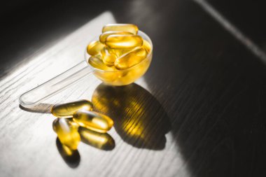 Omega 3 balık yağı sarı kapsüller plastik bir kaşık içinde, diyet takviyesi koyu ahşap tahta üzerinde, sağlıklı beslenme konsepti, yakın görüş.