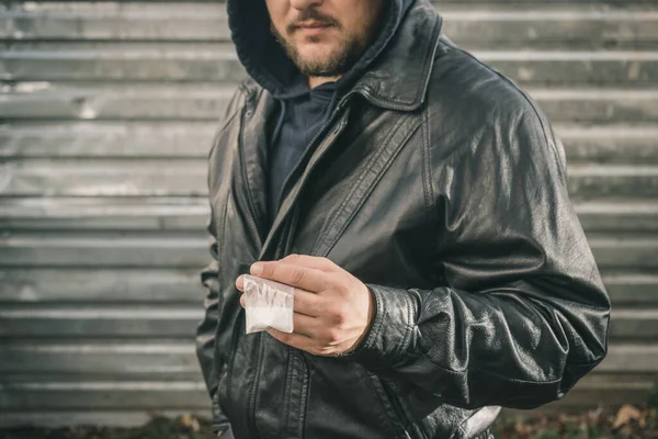 Tehlikeli uyuşturucu satıcısı, elinde beyaz toz narkotik maddeler bulunan şeffaf plastik torba tutarak sert uyuşturucu satıyor..