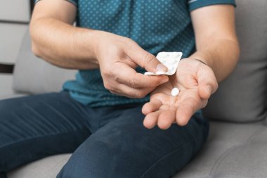 Su toplayıcıdan ilaç alan bir adam, elinde beyaz terapi hapı, antibiyotik, elinde ağrı kesici, yakın plan görüntüsü olan....