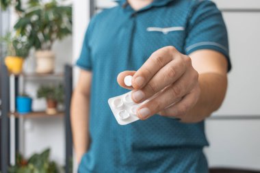 Su toplayıcıdan ilaç alan bir adam, elinde beyaz terapi hapı, antibiyotik, elinde ağrı kesici, yakın plan görüntüsü olan....