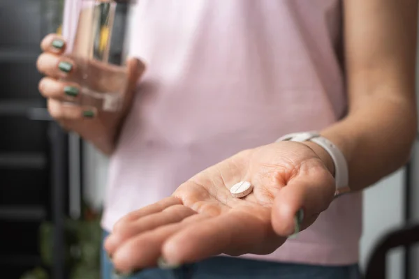Junge Frau Nimmt Tabletten Schmerzmittel Oder Antibiotika Und Hält Glas lizenzfreie Stockbilder