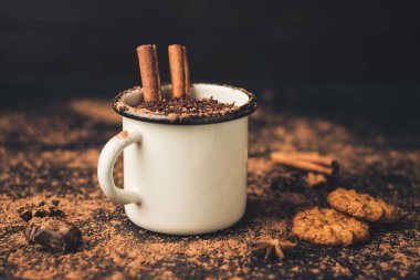 Tarçın çubuklu ev yapımı acılı sıcak çikolata, yıldız anason, koyu arka planda diş mineli çikolata, kakao tozu ve çikolata parçacıkları..