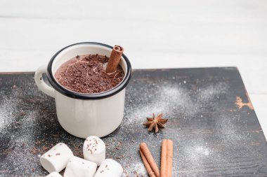 Tarçın çubuklu ev yapımı acılı sıcak çikolata, ahşap masada rendelenmiş çikolata, beyaz marşmelov ve yıldız anason..