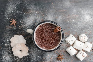 Tarçın çubuklu ev yapımı acılı sıcak çikolata, ahşap masada mineli çikolatalı kurabiye, beyaz marşmelov ve yıldız anason..