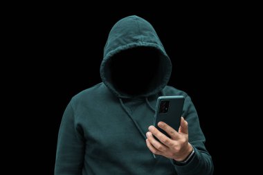 Gizemli yüzsüz, kimliği belirsiz, bilgisayar korsanı elinde akıllı telefon, siber suçlunun silueti, terörist.