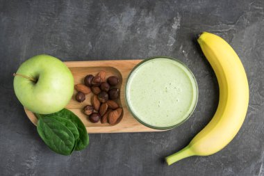 Bardakta yeşil detoks smoothie, ıspanak yaprakları, elma, muz ve fındık karışımı koyu fındık, sağlıklı beslenme konsepti, üst görünüm..