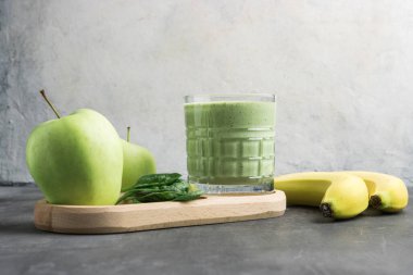 Bardakta yeşil detoks smoothie, ıspanak yaprakları, elma ve muz meyvelerinden karışık vejetaryen içeceği, sağlıklı beslenme kavramı..