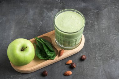 Bardakta yeşil detoks smoothie, ıspanak yaprakları, elma, muz ve fındık karışımı koyu arka planda sağlıklı beslenme konsepti..