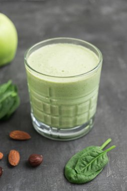 Bardakta yeşil detoks smoothie, ıspanak yaprakları, elma, muz ve fındık karışımı koyu arka planda sağlıklı beslenme konsepti..