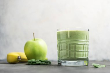 Bardakta yeşil detoks smoothie, ıspanak yaprakları, elma ve muz meyvelerinden karışık vejetaryen içeceği, sağlıklı beslenme kavramı..