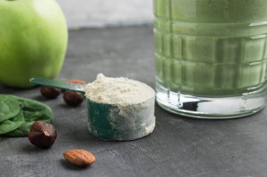 Yeşil detoks içeceği, bardakta milkshake, sağlıklı beslenme konsepti olan bir masada protein tozuyla ölçme kaşığı..