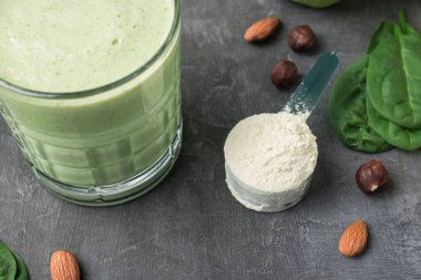 Yeşil detoks içeceği, bardakta milkshake, sağlıklı beslenme konsepti olan bir masada protein tozuyla ölçme kaşığı..
