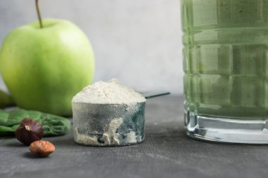 Yeşil detoks içeceği, bardakta milkshake, sağlıklı beslenme konsepti olan bir masada protein tozuyla ölçme kaşığı..
