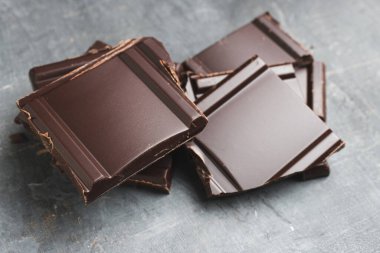 Lezzetli siyah çikolata parçacıkları ya da küp şeklinde siyah bir arka planda parçalanmış çikolata..