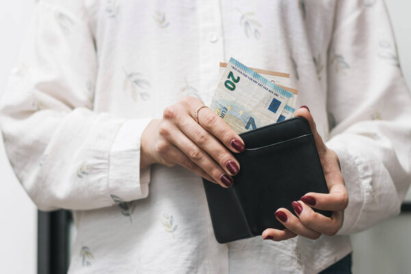 Woman's hands taking out money from wallet, euro banknote cash.