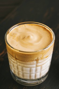 Dalgona kahvesi, çırpılmış kahve ve tahta bir bardakta sütle kokteyl..
