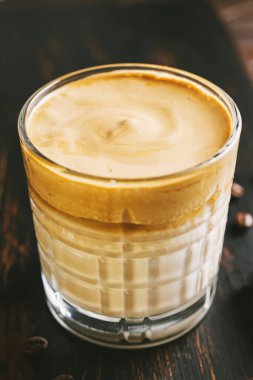 Dalgona kahvesi, çırpılmış kahve ve tahta bir bardakta sütle kokteyl..