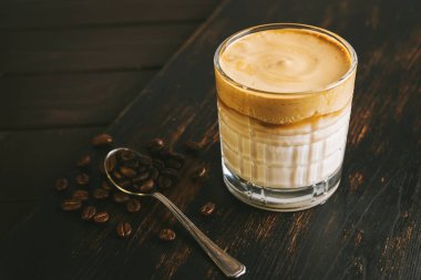 Dalgona kahvesi, çırpılmış kahve ve tahta bir bardakta sütle kokteyl..