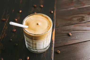 Dalgona kahvesi, çırpılmış kahve ve tahta bir bardakta sütle kokteyl..