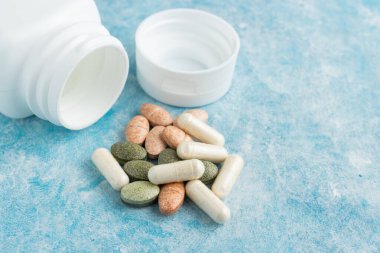 Mavi arka plan, vitamin ve mineraller, besin veya beslenme takviyesi için çok renkli tıbbi haplar, kapsüller, ilaçlar veya tabletler.