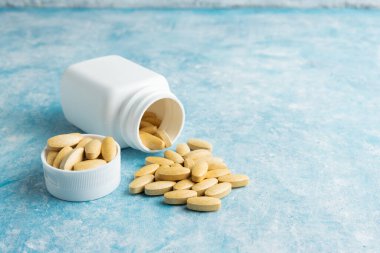 Mavi arka plan, vitamin ve mineraller, besin ya da beslenme takviyesi, tedavi için sarı ilaç ya da tabletler.