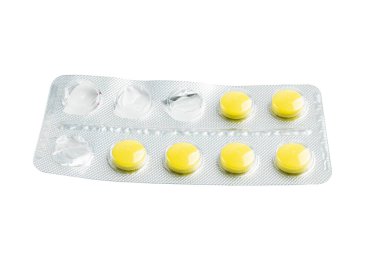 Beyaz arka plan, sağlık ve tıp konseptine izole edilmiş su toplayan bir pakette sarı ilaç hapları.