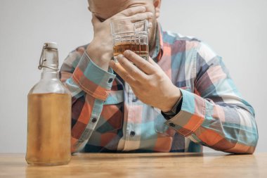 Masada bir bardak alkol, viski ya da brendi, alkolizm ve kötü alışkanlıklar ile bağımlı ve sarhoş bir adam var..
