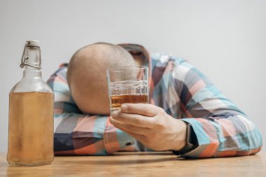 Masada bir bardak alkol, viski ya da brendi, alkolizm ve kötü alışkanlıklar ile bağımlı ve sarhoş bir adam var..