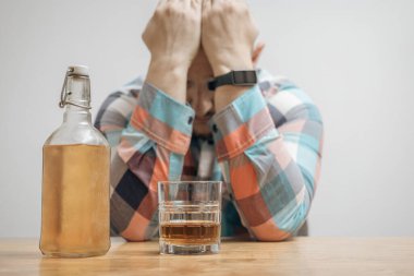 Masada bir bardak alkol, viski ya da brendi, alkolizm ve kötü alışkanlıklar ile bağımlı ve sarhoş bir adam var..